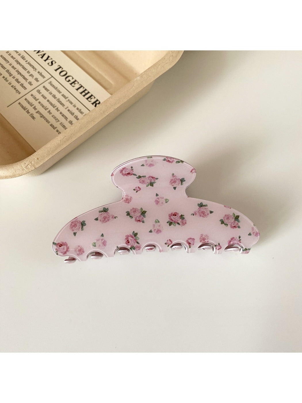 Beau hair claw clip placed on a wooden surface showing floral pattern