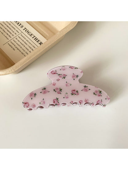 Beau hair claw clip placed on a wooden surface showing floral pattern
