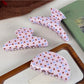Beau pink polka dot claw clip held in hand showing size and crescent shape