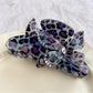 Beau claw clip styled in hair with leopard print and butterfly decoration visible