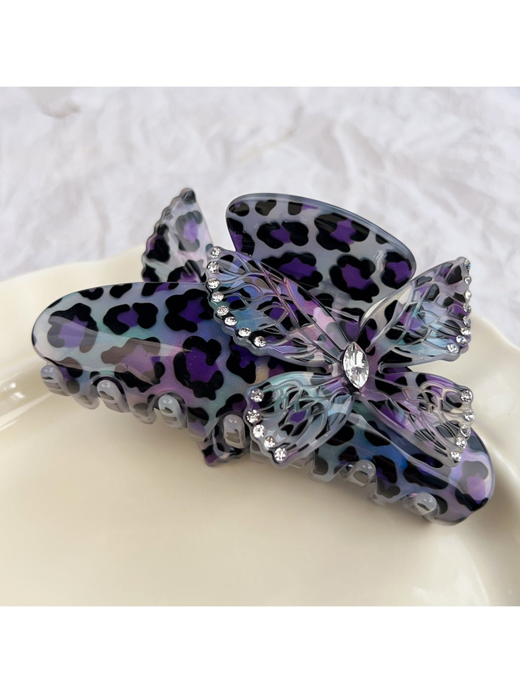 Beau claw clip styled in hair with leopard print and butterfly decoration visible