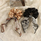 Close-up of vintage satin bow hair scrunchie in soft pink on white background