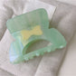 Beau elegant hair claw clip placed on a white surface with soft shadows