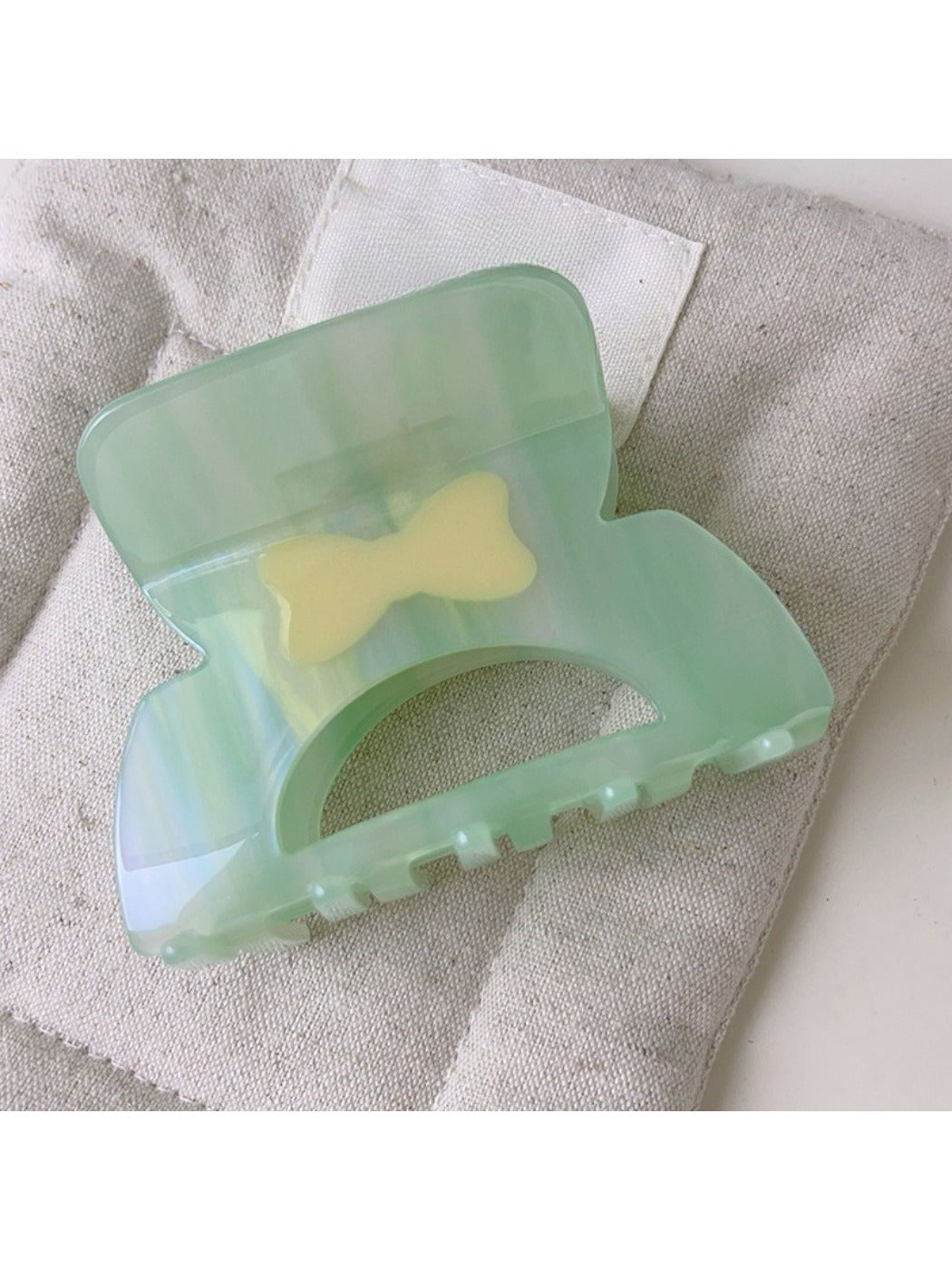 Beau elegant hair claw clip placed on a white surface with soft shadows