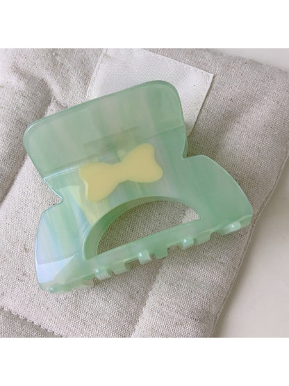 Beau elegant hair claw clip placed on a white surface with soft shadows