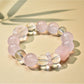 Pink beaded bracelet with gold details laid flat on a textured surface