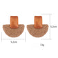 Pair of raffia mushroom shaped stud earrings displayed on a wooden surface