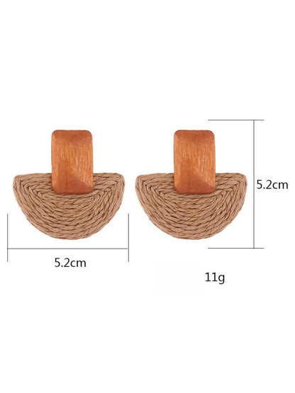 Pair of raffia mushroom shaped stud earrings displayed on a wooden surface