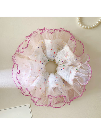 Scrunchie with vibrant polka dots and ruffled edges displayed flat