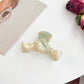 Beau minimalist bow shaped claw clip on a neutral fabric background