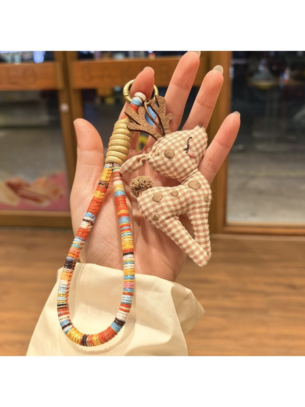 Hand holding the stylish deer charm keychain with natural lighting