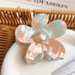 Flower-shaped hair claw clip with vibrant colors placed on a wooden surface