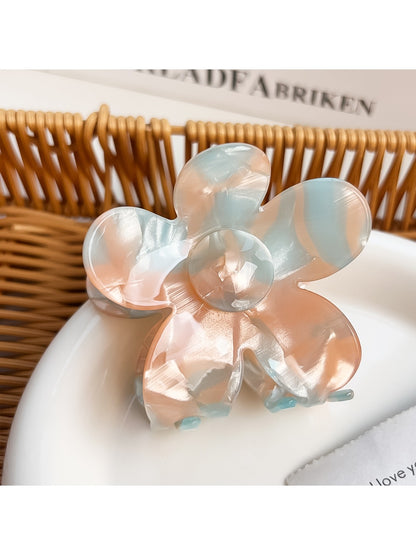 Flower-shaped hair claw clip with vibrant colors placed on a wooden surface
