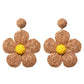 Pair of earedge knitted flower earrings placed on a light fabric background