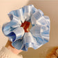 Model holding Gifty satin ruffle scrunchie with manicured nails, showcasing size