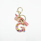 Butterfly letter pendant keychain shown from a side angle on a white surface