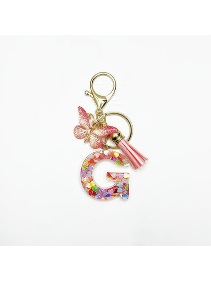 Butterfly letter pendant keychain shown from a side angle on a white surface