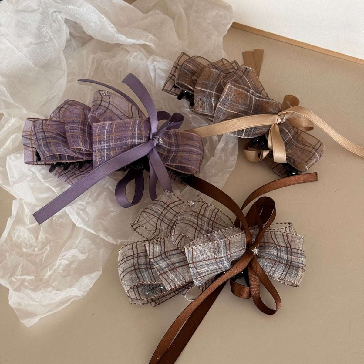 Beau checkered bow hair clip displayed on a wooden surface showing the clip mechanism