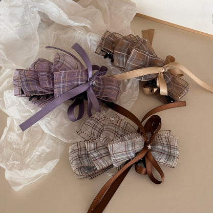 Beau checkered bow hair clip displayed on a wooden surface showing the clip mechanism