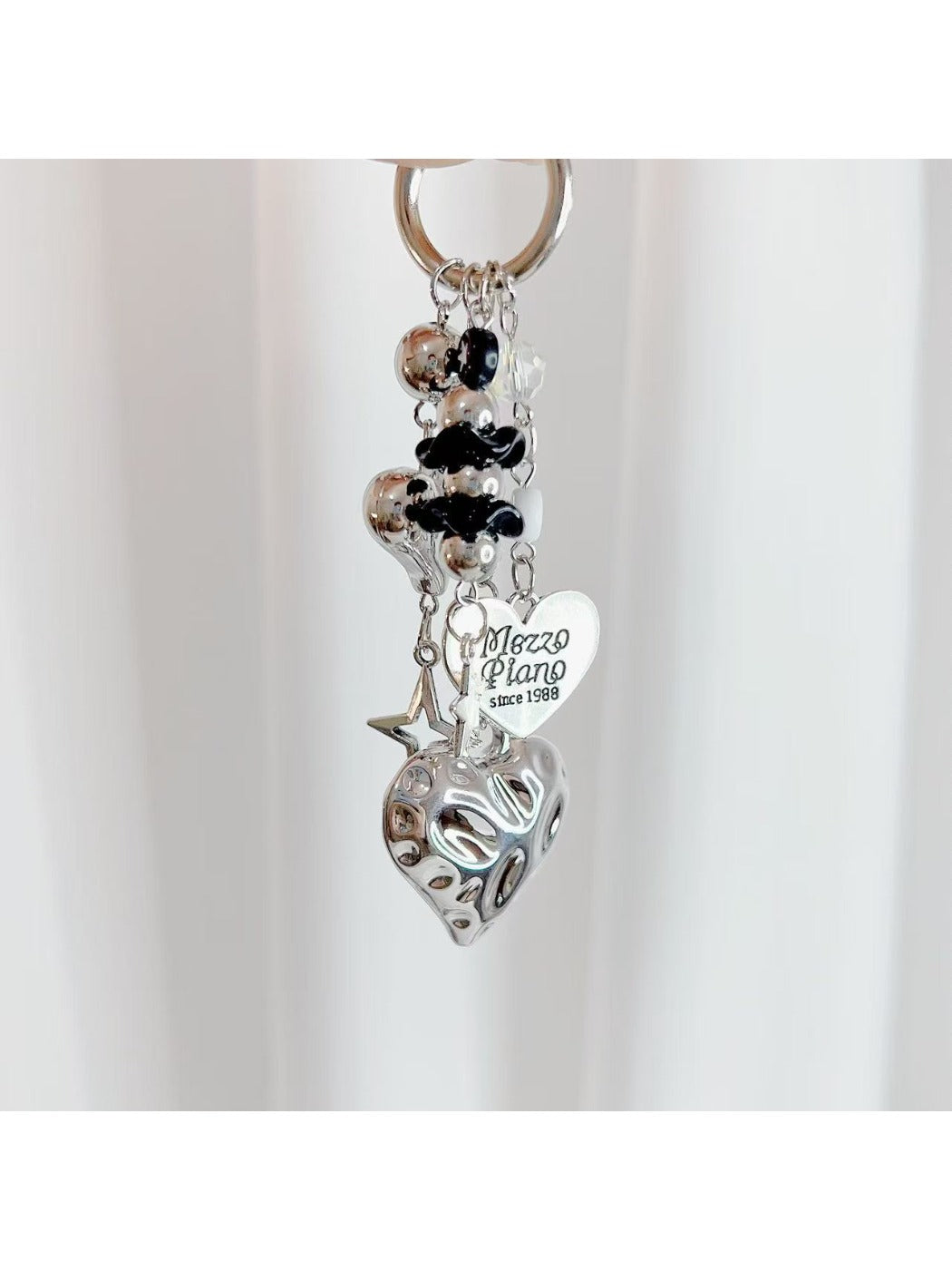 Heart shaped charm keychain displayed hanging from a hook against a neutral backdrop