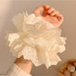 Close-up of white ruffled scrunchie showing soft, fluffy texture