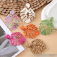 Close-up of Earedge raffia woven hollow leaf shaped earring on white background