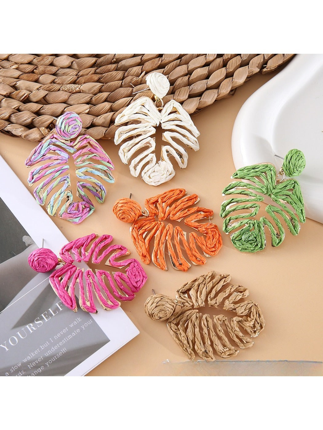 Close-up of Earedge raffia woven hollow leaf shaped earring on white background