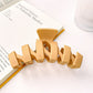 Beau hair claw clip resting on wooden surface highlighting matte finish