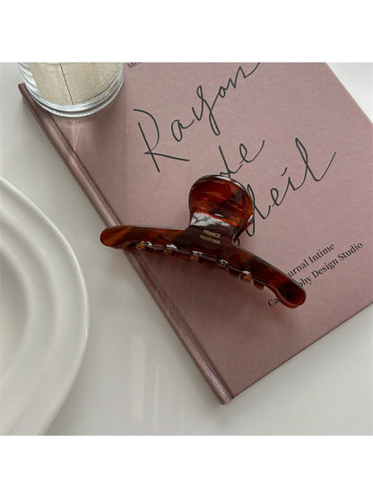Beau elegant chic claw clip resting on a wooden surface with soft lighting