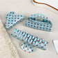 Blue hair claw clip with white polka dots held in hand