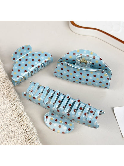 Blue hair claw clip with white polka dots held in hand