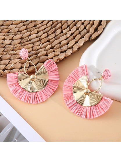 Earedge raffia fan earrings placed on a natural fabric surface
