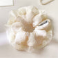 White ruffle scrunchie placed next to matching hair accessories