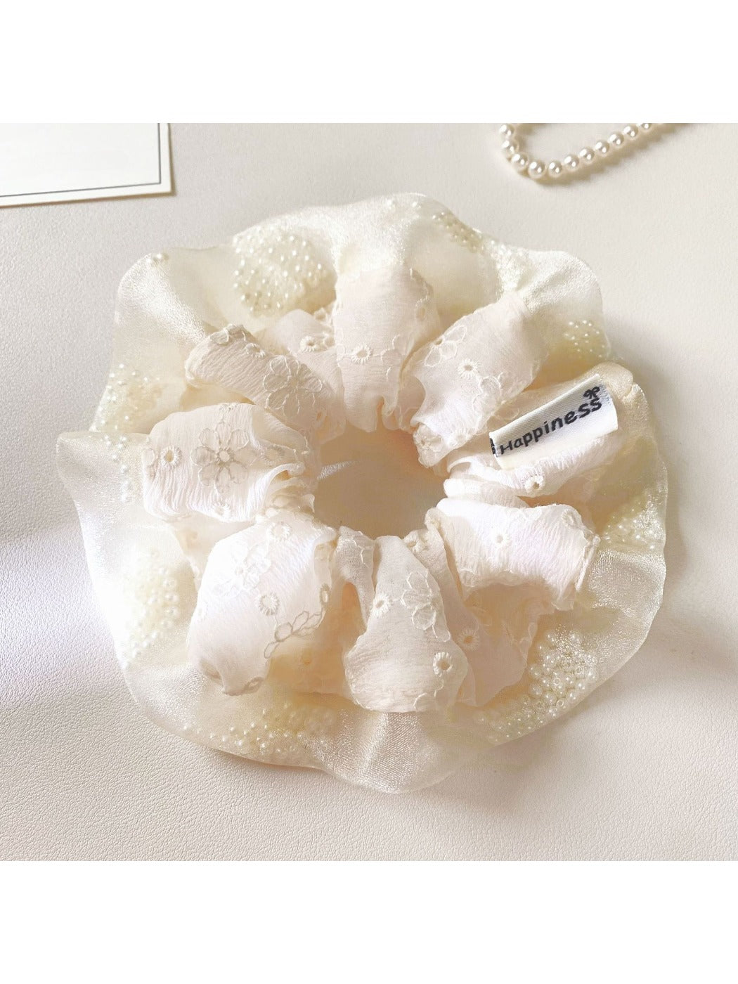 White ruffle scrunchie placed next to matching hair accessories