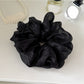 Multiple solid color scrunchies stacked together showing variety