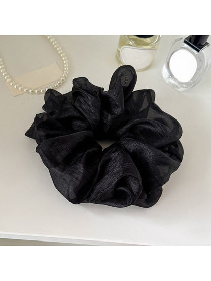 Multiple solid color scrunchies stacked together showing variety