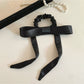 Top view of a satin bow hair tie showing the elastic band and bow detail