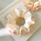 Close-up of pink ruffle beige scrunchie on white background