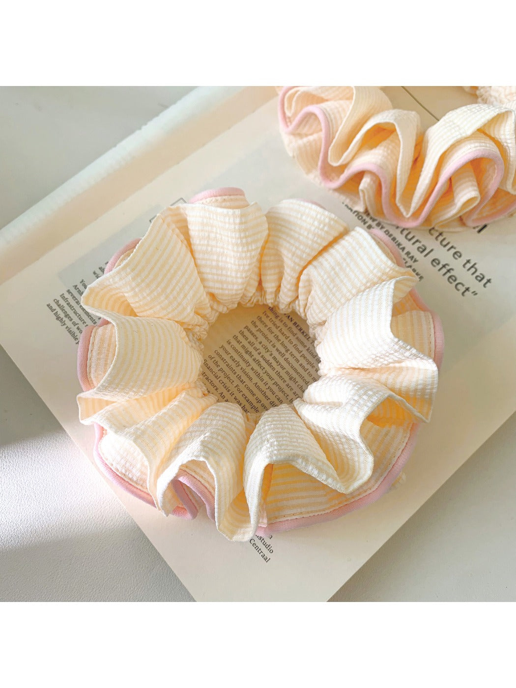 Close-up of pink ruffle beige scrunchie on white background