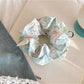 Blue scrunchie with ruffled edges held in a hand