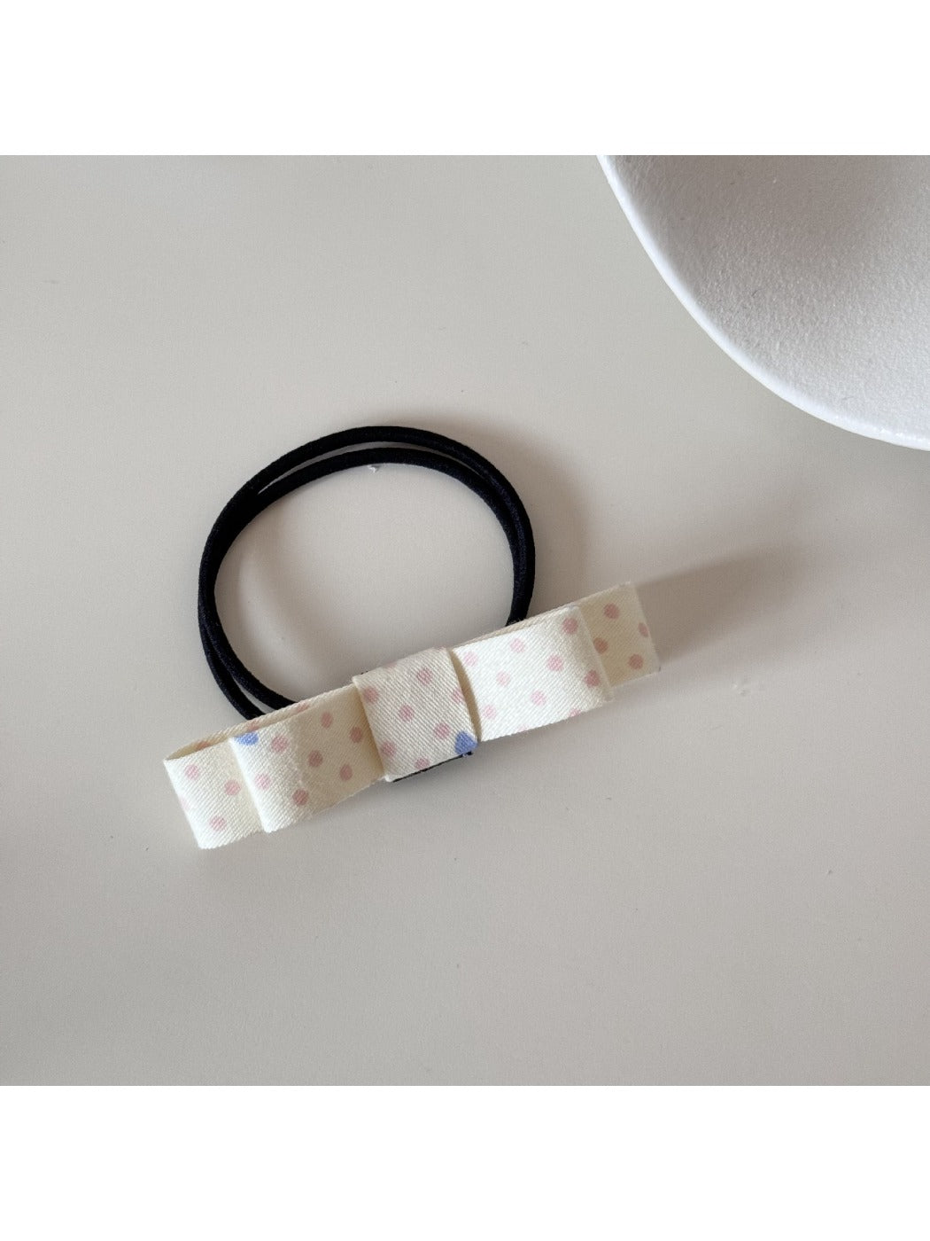 Hair tie with a pink bow placed next to matching pink accessories