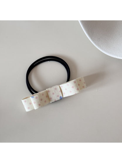 Hair tie with a pink bow placed next to matching pink accessories