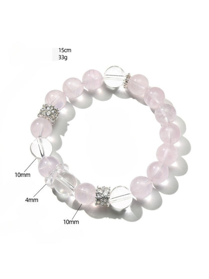 Lovra pink and white crystal beaded bracelet coiled on a reflective surface