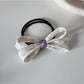 Gifty bow embellished printed hair tie placed on wooden surface