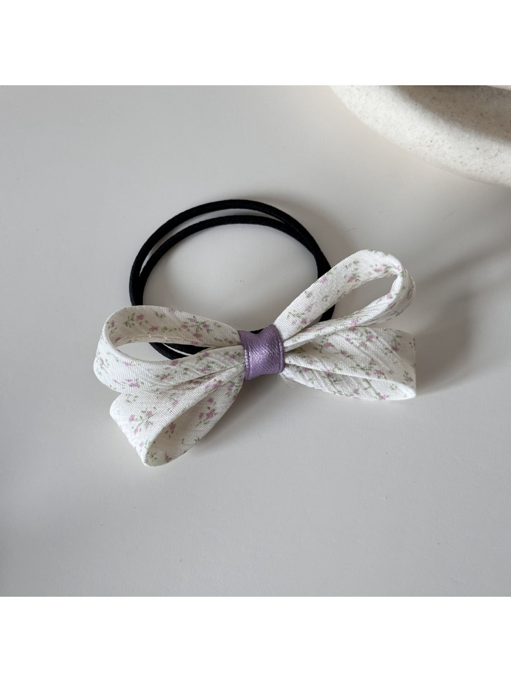 Gifty bow embellished printed hair tie placed on wooden surface