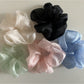 Minimalist sheer tulle scrunchie in soft beige on white background
