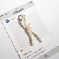 Keypus bow keychain displayed hanging from a hook with light background