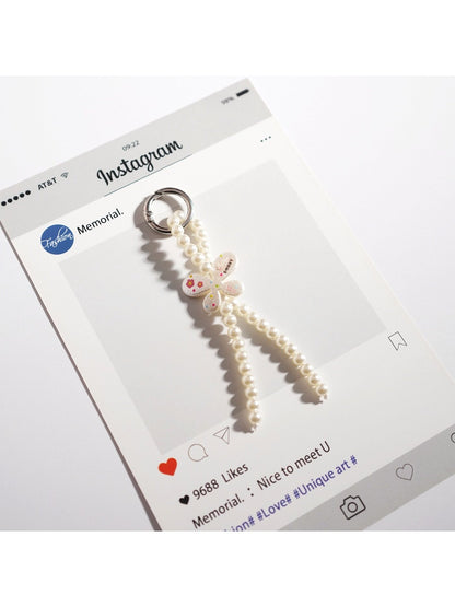 Keypus bow keychain displayed hanging from a hook with light background
