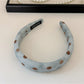 Blue polka dot headband folded next to scrunchie on a white background