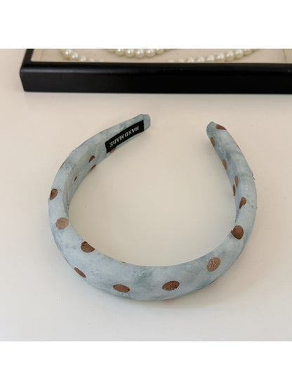 Blue polka dot headband folded next to scrunchie on a white background